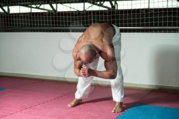 Male Martial Arts Instructor Preparing For Class - Warming Up and Stretching