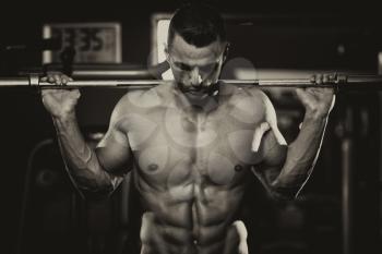 Young Man Performing Barbell Squats - One Of The Best Bodybuilding Exercise For Legs