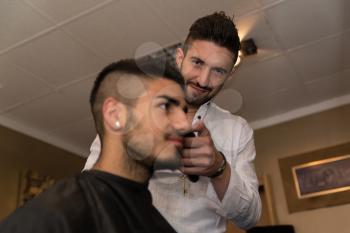 Handsome Young Hairdresser Giving A New Haircut To Male Customer At Parlor