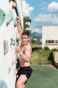 Young Man Climbs Up An Outdoors Rock Wall - He Is Clearly Determined To Make It To The Top