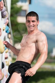 Young Man Climbs Up An Outdoors Rock Wall - He Is Clearly Determined To Make It To The Top