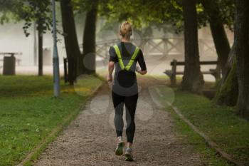 Young Woman Running In Wooded Forest Area - Training And Exercising For Trail Run Marathon Endurance - Fitness Healthy Lifestyle Concept