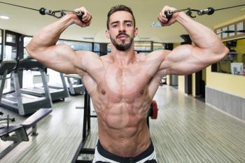 Young Man Bodybuilder Is Working On His Biceps With Cables In A Gym