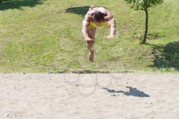 Muscular Young Man Playing Beach Volleyball Diving After The Ball