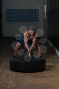 Athletic Man Hits Tire - Workout At Gym With Hammer And Tractor Tire