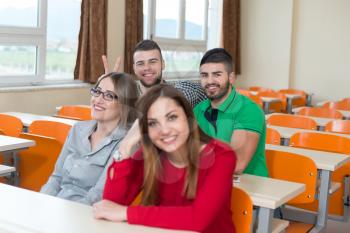 Young Group Of Attractive Teenage Students In A College Classroom Sitting At A Table - Learning Lessons