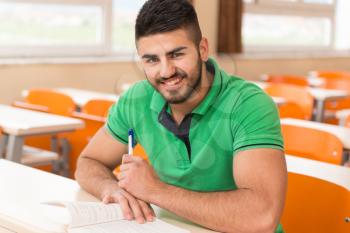 Portrait Of Young Arabic Male College Student With Book Sitting In Classroom Alone