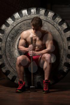 Athletic Man Resting - Workout At Gym With Hammer And Tractor Tire