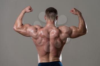 Serious Man Standing Strong In The Gym And Flexing Muscles