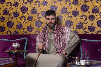 Muslim Man Smoking Turkish Hookah In The Cafe With Colorful Walls On Background