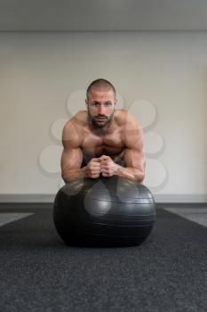 Young Man Exercising Abs On Ball Workout Posture In Fitness Club