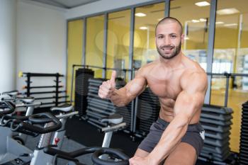 Man In The Gym Showing Thumbs Up - Exercising His Legs Doing Cardio Training On Bicycle