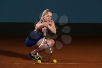 Portrait Of Female Tennis Player With Racket Ready To Hit A Tennis Ball