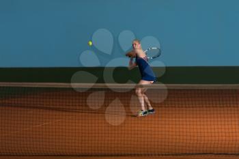 Female Tennis Player Reaching To Hit The Tennis Ball On Court