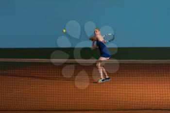 Female Tennis Player Reaching To Hit The Tennis Ball On Court