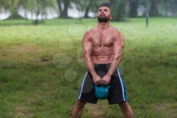 Muscular Adult Caucasian Man Doing A Exercise Outdoors With Kettlebell