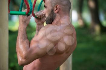 Close-Up Muscular Built Young Athlete Working Out In An Outdoor Gym - Doing Chin-Ups