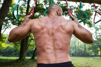 Close-Up Muscular Built Young Athlete Working Out In An Outdoor Gym - Doing Chin-Ups