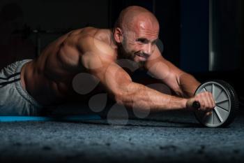 Young Man Exercising Fitness Workout For Abdominal With Toning Wheel