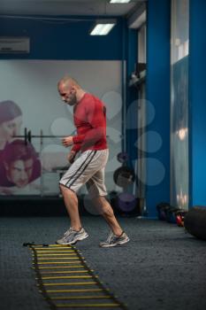 Handsome Man Running On Step Ladders Lying On Floor - Sports And Fitness - Concept Of Healthy Lifestyle - Fitness Male