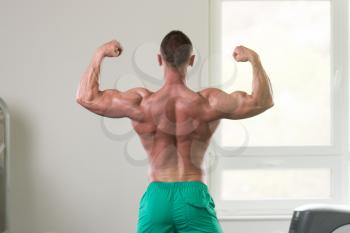 Young Man Standing Strong In The Gym And Flexing Muscles - Muscular Athletic Bodybuilder Fitness Model Posing After Exercises