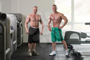Two Guys Standing Strong In The Gym And Flexing Muscles - Muscular Athletic Bodybuilder Fitness Model Posing After Exercises
