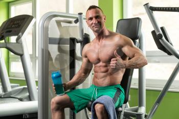 Muscular Man Resting After Exercise And Drinking From Shaker While Showing Thumbs Up