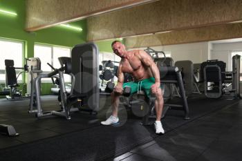 Muscular Young Man Doing Heavy Weight Exercise For Biceps With Dumbbell In Modern Fitness Center Gym