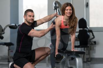 Personal Trainer Showing Young Woman How To Train Back Exercise With Dumbbell In A Gym