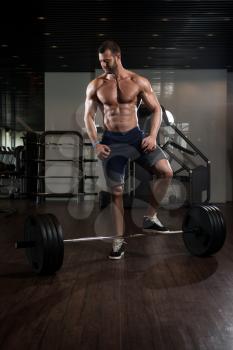 Young Bodybuilder Doing Heavy Weight Exercise For Back With Barbell In Modern Gym