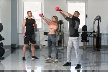Young Woman And Men Doing Exercise With Kettle Bell In The Gym