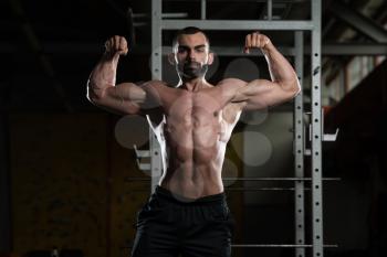 Portrait Of A Young Fit Man Performing Front Double Biceps Pose - Muscular Athletic Bodybuilder Fitness Model Posing After Exercises