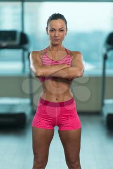 Young Woman Standing Strong In The Gym And Flexing Muscles - Muscular Athletic Bodybuilder Fitness Model Posing After Exercises