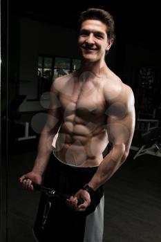 Young Muscular Fitness Bodybuilder Doing Heavy Weight Exercise For Biceps On Machine With Cable In The Gym