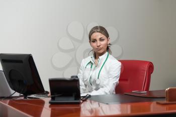 Portrait Of A Young Female Doctor Using Computer At Office - Healthcare Worker Working Online
