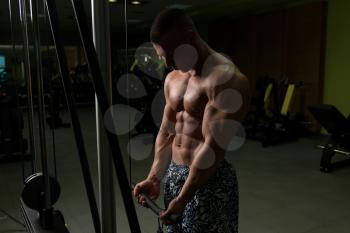Young Muscular Fitness Bodybuilder Doing Heavy Weight Exercise For Biceps On Machine With Cable In The Gym
