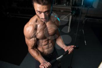 Handsome Muscular Fitness Bodybuilder Doing Heavy Weight Exercise For Biceps On Machine With Cable In The Gym