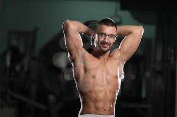 Handsome Man Wearing Glasses Working Out Triceps With Dumbbell In A Dark Gym