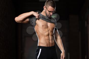 Portrait Of A Young Physically Fit Nerd Man Showing His Well Trained Body In Sports Clothing - Muscular Athletic Bodybuilder Fitness Model Posing After Exercises