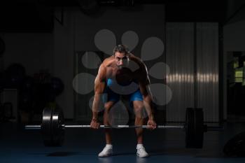 Muscular Hispanic Man Doing Heavy Weight Exercise For Back With Barbell In Modern Gym