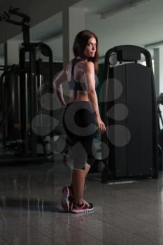 Fitness Woman Standing Strong In The Gym And Flexing Muscles - Muscular Athletic Bodybuilder Model Posing After Exercises