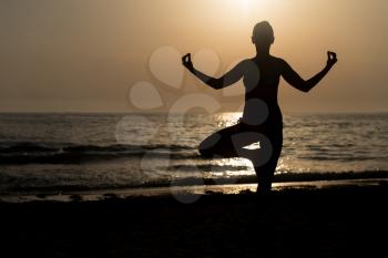 Young Healthy Woman Practicing Yoga Fitness Exercise on the Beach at Sunset - Healthy Lifestyle Concept - Copy Space Text