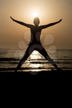 Silhouette of Woman With Raised Hands And Jumping Around on the Beach at Sunset - Copy Space Text