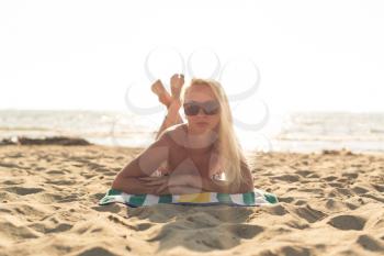 Young Tourist Girl Lying Down on Towel by Sea Wearing Bikini and Sunglasses Enjoying Summer Travel Holidays