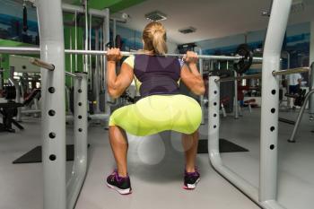 Mature Woman Working Out Legs With Barbell In A Gym - Squat Exercise - Muscular Athletic Bodybuilder Fitness Model