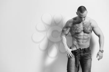 Portrait of a Sexy Naked Man In Jeans Showing His Abdominal Standing Isolated on Gray Background