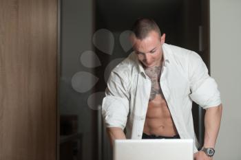 Man Working From Home on a Laptop Computer Standing at a Desk Surfing the Internet