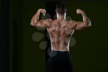 Handsome Man Standing Strong In The Gym And Flexing Muscles - Muscular Athletic Bodybuilder Fitness Model Posing After Exercises