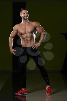 Healthy Man Standing Strong In The Gym And Flexing Muscles - Muscular Athletic Bodybuilder Fitness Model Posing After Exercises