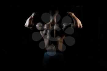 Handsome Man Standing Strong In The Gym And Flexing Muscles - Muscular Athletic Bodybuilder Fitness Model Posing After Exercises